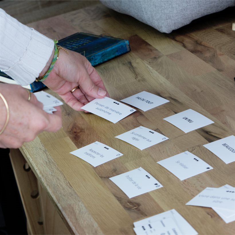 Magalie étale des cartes sur un bureau pendant une séance de coaching avec des personnes neuro-sensiblessonnes 